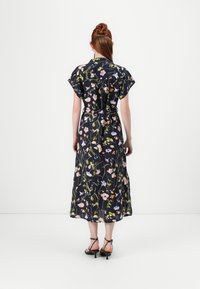 Navy maxi-kjole med blomsterprint, korte flakkende ermer, innsvingt midje og beltedetaljer. Har varierte blomster mønstre gjennom hele kjolen.