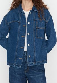 Tummansinisestä farkkutakista, jossa on klassinen leikkaus, leveä kaulus, etupainikkeet, rintatasku ja kontrastiväriset tikkaus yksityiskohdat.