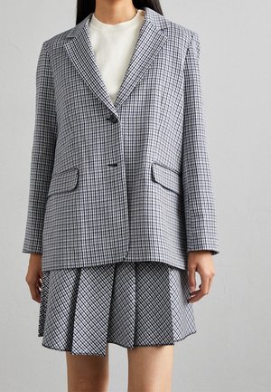 Tjekket blazer og plisseret nederdel i sort og hvid. Blazeren har en spids krave og to forlommer. Tekstiler med struktureret pasform.