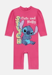 Ružičasti kombinezon s dugim rukavima, s grafikom Stića, uz tekst "Slatko i pahuljasto" u šarenim, podebljanim slovima.