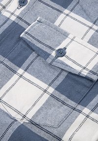 Μπλε και λευκό καρό φλιάνελο ύφασμα με τσέπη patch, διακοσμημένο με μπλε κουμπιά, υφή υφάσματος και αντίθετα μοτίβα γραμμών.