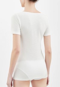 Camicia bianca a maniche corte con scollo rotondo, realizzata in materiale morbido e leggero. Design aderente, minimalista, senza motivi o accenti visibili.
