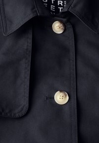 Czarna kurtka uszyta z gładkiego materiału, z wyrazistym kołnierzem oraz dwoma kremowymi guzikami z czterema otworami.