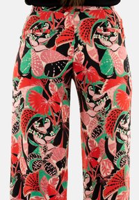 Pantalons à jambe large multicolores avec un motif floral rouge, rose, vert et noir ; fabriqués en tissu léger avec des poches latérales.