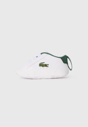 White infant shoe with a rounded toe, green accents at the heel and laces, and a green embroidered crocodile logo on the side.