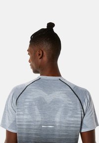 Grey athletic t-shirt featuring a textured design with varying stripes, contrasting black stitching, and a fitted silhouette.