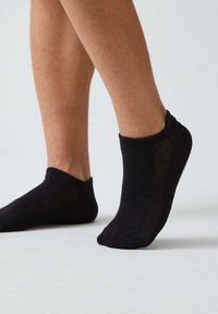 Calze nere alla caviglia realizzate in un materiale liscio ed elastico, con polsino a coste e pannello laterale testurizzato. Design aderente che copre la caviglia.