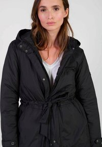 Zwarte pufferjack met een capuchon, getailleerde taille en drukknoopsluitingen. Bevat een rits, een gladde textuur en een schoon, minimalistisch ontwerp.