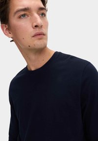 Maglietta a maniche lunghe di colore blu navy con colletto rotondo, realizzata in tessuto morbido, presenta un design classico con colletto a costine e una texture liscia, con dettagli di cucitura minimi.