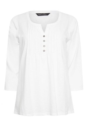 Hvid bluse med lange ærmer, rund udskæring med udskæring, fire dekorative knapper, lodrette læg foran, størrelseetiket inde i kraven.