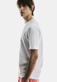 Vit kortärmad t-shirt med rund halsringning, med en subtil logotyp. Tillverkad av mjukt tyg, med en avslappnad passform och en ren design.