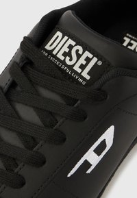 Must nahast toss mustade paeltega. Omab valget "A" logo ja kaubamärgiga keeletähist, millel on kirjas "DIESEL" ja "FOR SUCCESSFUL LIVING."