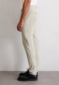 Lichtbeige broek met een rechte pijpdesign, gemaakt van zachte katoen, met zijzakken en een achterzak met knoopsluiting.