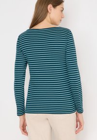 Maglietta teal a maniche lunghe con strisce orizzontali azzurre, con scollatura a barca e un design aderente, realizzata in un tessuto morbido.