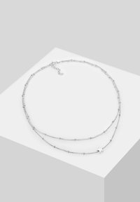 Silver-tone layered necklace featuring fine links with small bead accents and a star charm. Adjustable length with a lobster clasp.