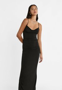 Schwarzes ärmelloses Kleid mit tailliertem Schnitt, schulterfreier Halsschneider und geraffter Textur an der Seite. Glattes Material, bodenlanger Schnitt.
