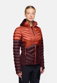 Die Herren-Steppjacke präsentiert sich in einem zweifarbigen Design in Orange und Burgunderrot. Sie verfügt über eine Kapuze, einen Reißverschluss und eine strukturierte Chevron-Steppung.