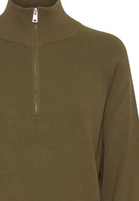 Maglione a coste color verde oliva con colletto alto e zip argentata a un quarto nella parte centrale anteriore.