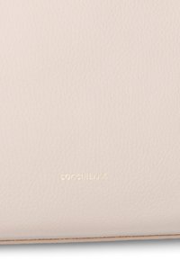 Portafoglio in pelle rosa pallido con superficie testurizzata, caratterizzato da logo in rilievo dorato, design minimalista e forma rettangolare piatta.