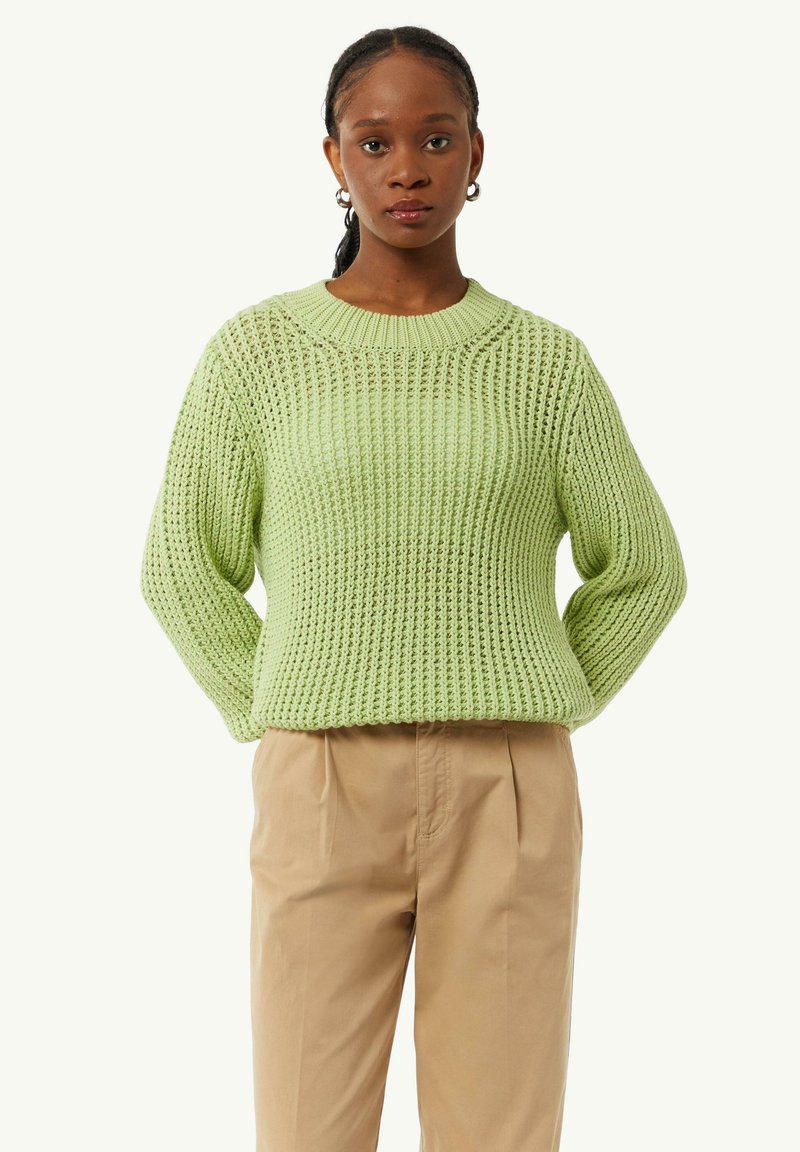 Pull en tricot vert clair avec un col rond et une texture lâche et côtelée. Il a des manches larges et une coupe légèrement courte.