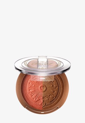 Gesloten ronde compacte met een doorzichtig deksel die een geperst tweekleurig bronzer toont in koper- en bronstinten met zonnestraal- en hartontwerp.