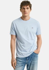 Lichtblauwe katoen t-shirt met een ronde hals en korte mouwen, voorzien van een klein logo op de borst en een relaxte pasvorm. Gecombineerd met een blauwe spijkerbroek.
