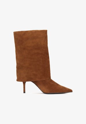 Bruine suède enkellaars met een puntige neus en een hoge schacht, voorzien van een slanke naaldhak en een gladde textuur.
