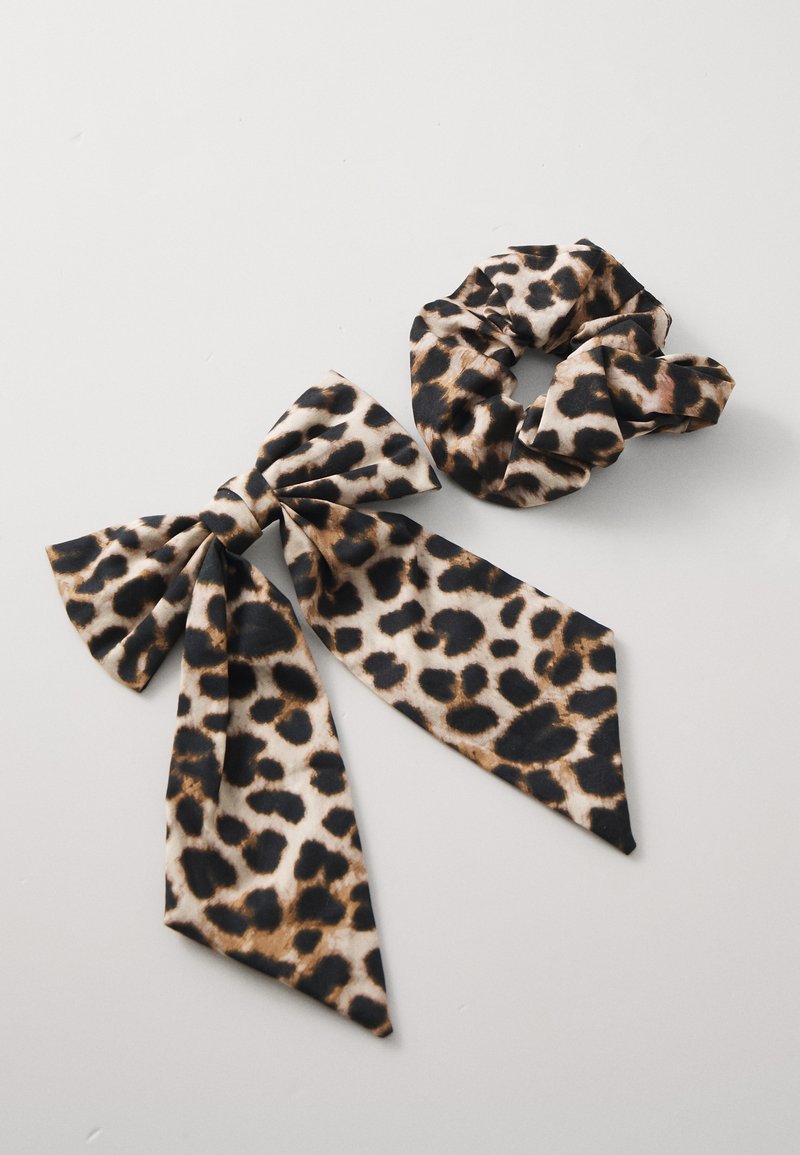 Saten traka za kosu s leopard uzorkom i dugim vezicama te odgovarajućim gumicom za kosu, s crnim i smeškim točkicama na bež pozadini.