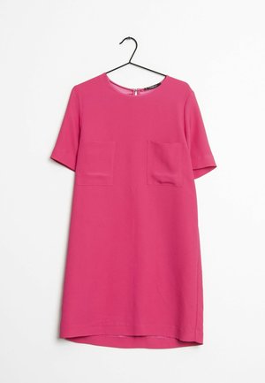 Robe rose vif à manches courtes, longueur genou, avec deux poches frontales, suspendue à un cintre noir sur un fond blanc.