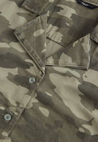 Camicia con motivo mimetico realizzata in tessuto strutturato. Presenta un colletto a punta, chiusura con bottoni e tonalità smorzate di verde e beige.