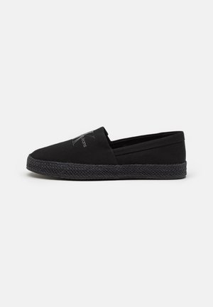 Czarny casualowy but typu slip-on z teksturowaną podeszwą i subtelnym logo na wierzchu, pokazany z boku na jednolitym tle.