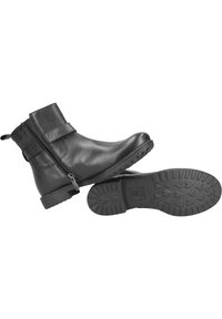 Botas de cuero negras hasta el tobillo con cierre de cremallera y una correa decorativa. Presentan una suela de goma texturizada con un patrón de corazones para mayor agarre.