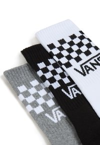 Tre paia di calzini con texture a coste e motivi a scacchi in nero, bianco e grigio. Ogni calzino presenta il logo 'VANS'.