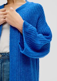 Blauwe gebreide cardigan met een losse structuur, lange mouwen en een getextureerde afwerking. Heeft een V-halsopening en een vloeiende silhoutte.