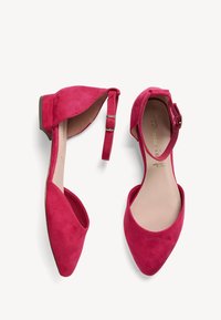 Paire de ballerines rouges en daim avec bride à la cheville, bouts pointus et petits talons, vues de dessus et de côté sur fond blanc.