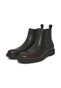 Stivali Chelsea in pelle marrone con pannelli elastici neri, punta arrotondata e suola in gomma testurizzata. Leggera lucentezza e dettagli di cucitura minimali.