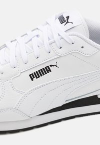 Baskets en cuir blanc avec dessus texturé, bout rond et accents noirs. Présentent un logo sur le côté, un laçage à l'avant et un col matelassé.