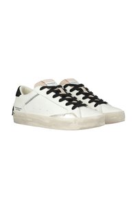 Basket d cuir blanc avec des lacets et des accents noirs, présentant une languette beige texturée et une semelle en caoutchouc transparent, légèrement usée.