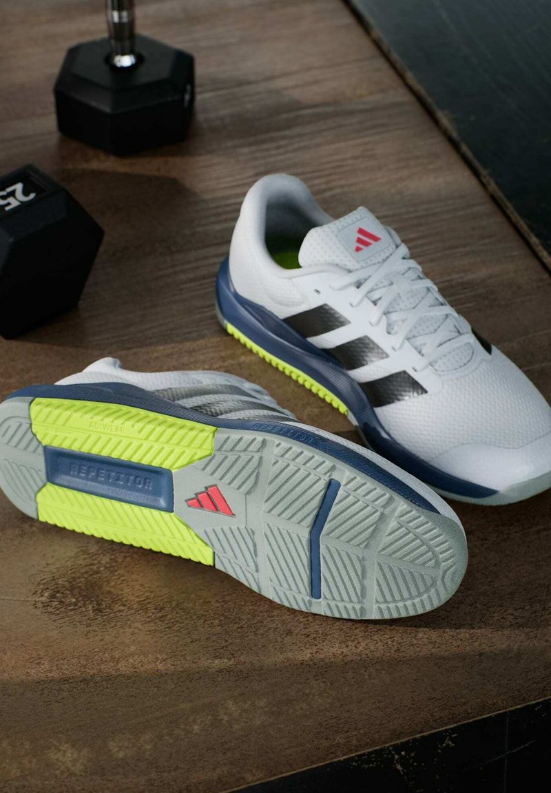 Białe buty sportowe z szarymi akcentami, trzema czarnymi paskami, podeszwa w kolorze szarym z bieżnikiem, z neonowymi zielonymi i czerwonymi detalami, oraz teksturowana siateczka na wierzchu.