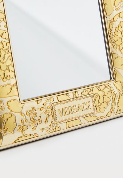 Χρυσή διακοσμητική κορνίζα με φυτικά μοτίβα και το λογότυπο "Versace". Λεία υφή με περίτεχνη λεπτομέρει�α γύρω από τις άκρες.