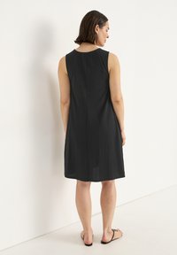 Schwarzes ärmelloses Kleid mit lässigem Schnitt, glatter Textur und knielangem Saum. Einfaches Design mit rundem Ausschnitt und minimalen Verzierungen.