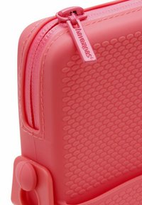 Coperchio in morbido colore rosa con superficie in gomma, dotato di chiusura a zip e un anello per la chiusura circolare. Include un manico laterale rotondo.
