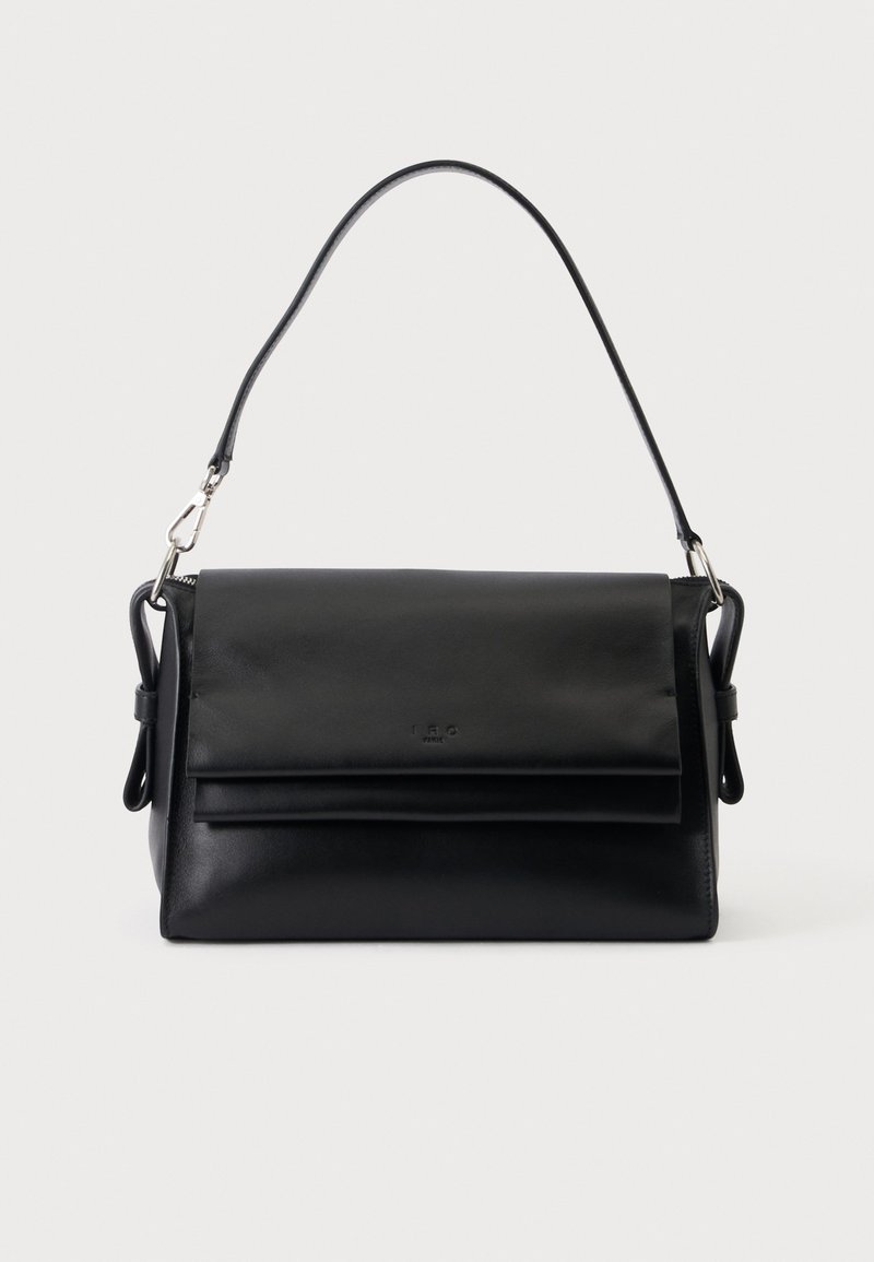 Sac à main en cuir noir avec une bandoulière unique, rabat pliant et une simple fermeture argentée sur un fond clair uni.