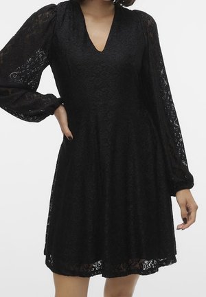 Schwarzes Spitzenkleid mit V-Ausschnitt, langen Puffärmeln und einem ausgestellten Rock. Filigranes Blumenmuster auf dem gesamten Stoff.