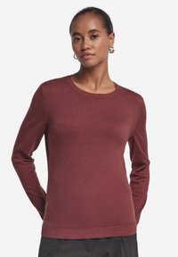Maglione bordeaux a maniche lunghe con scollo rotondo e polsini a costine. Realizzato in un tessuto morbido e strutturato, aderente al corpo.