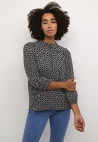 Bluse mit Marine-Muster und Rautenformen, runder Ausschnitt, Dreiviertelärmel und leichtem Stoff, kombiniert mit Jeans.