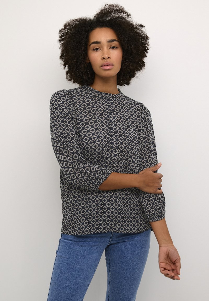 Bluse mit Marine-Muster und Rautenformen, runder Ausschnitt, Dreiviertelärmel und leichtem Stoff, kombiniert mit Jeans.