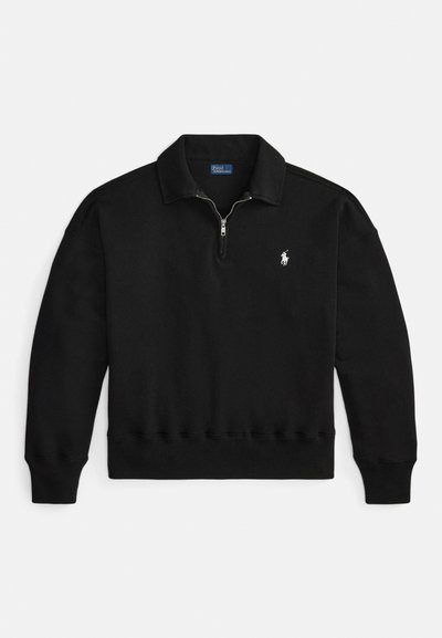 Juodas megztinis su ketvirtinės užtrauktuko apykakle, ribinėmis rankogaliais ir apačia, ant kairės krūtinės mažas baltas logotipas. Minkšta medžiagos tekstūra.