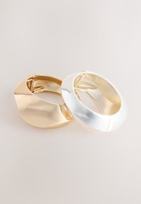 Goldene und silberne Creolen mit einer glatten, glänzenden Oberfläche und einem modernen Design, ausgestattet mit einem sicheren Scharnierverschluss.