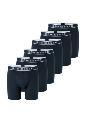 Sechs Paare schwarzer Herrenboxershorts, in versetzter Reihe angeordnet, jeweils mit weißem Bund mit der Aufschrift "SCHIESSER."